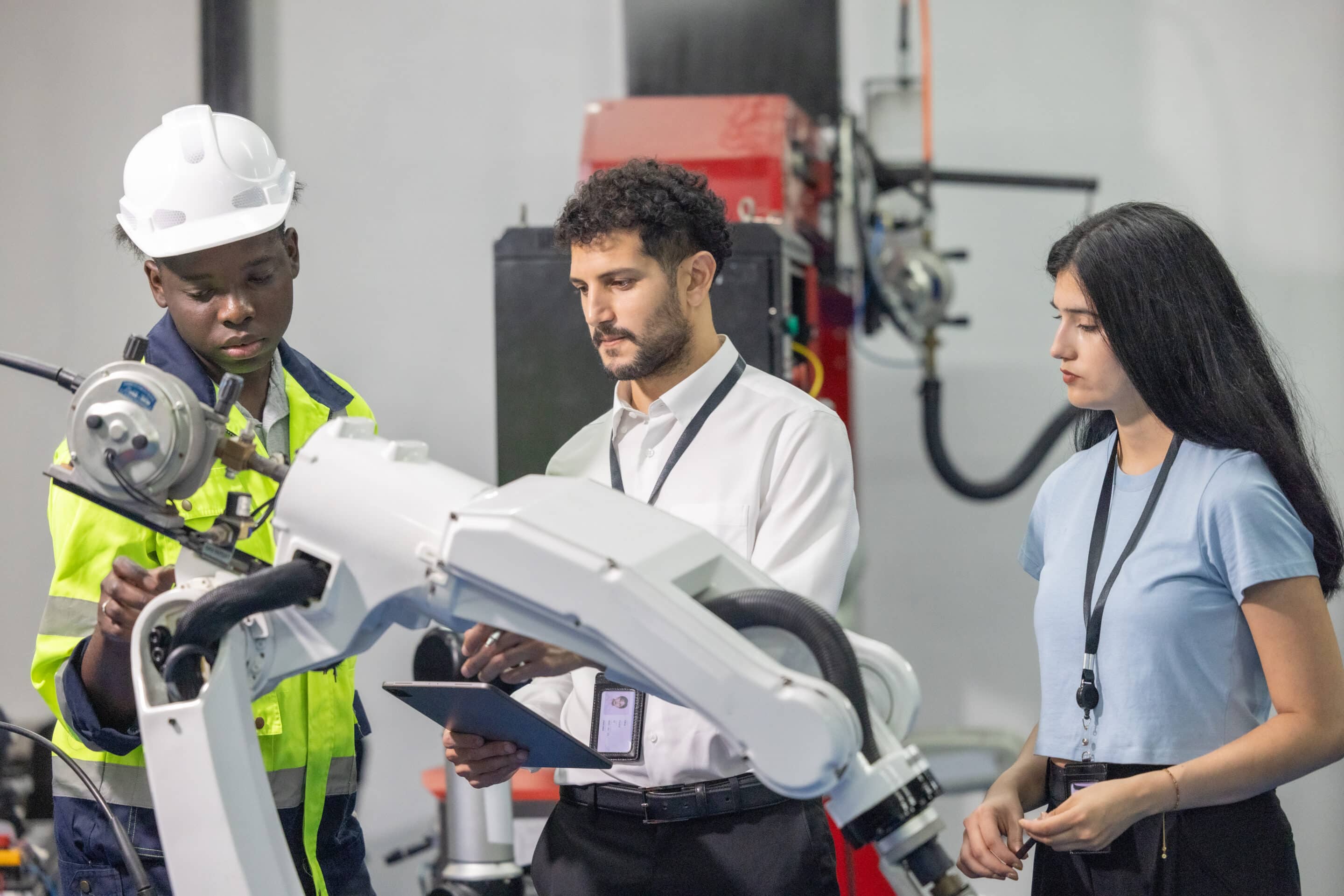 Three engineers analyzing OEE data on robotic hand demonstrating Industry 4.0 AI and IoT integration in manufacturing. OEE and Industrie 4.0
